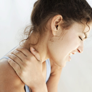 Young Woman Holding Her Neck in Pain --- Image by © Royalty-Free/Corbis